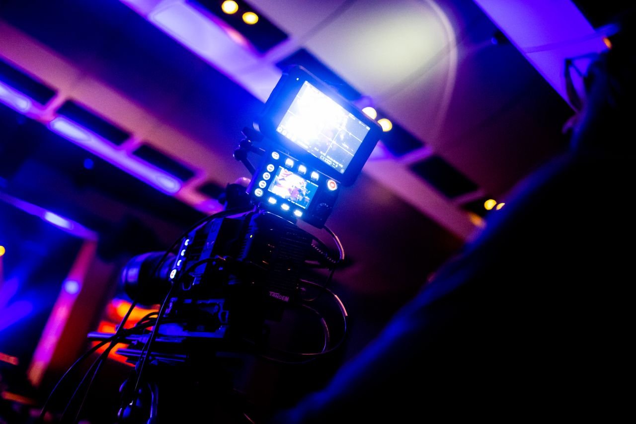 anniversay-04 Close-up of a high-tech video camera under vibrant studio lights, perfect for broadcasting and entertainment.