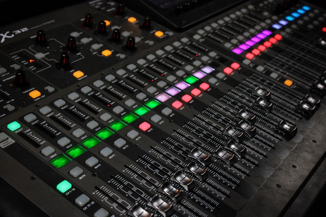 social-feed-img-01 Detailed view of audio mixing console with glowing LED buttons.