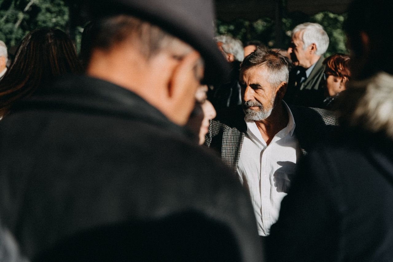 Bearded man in corporate attire amidst a diverse crowd at an outdoor event.