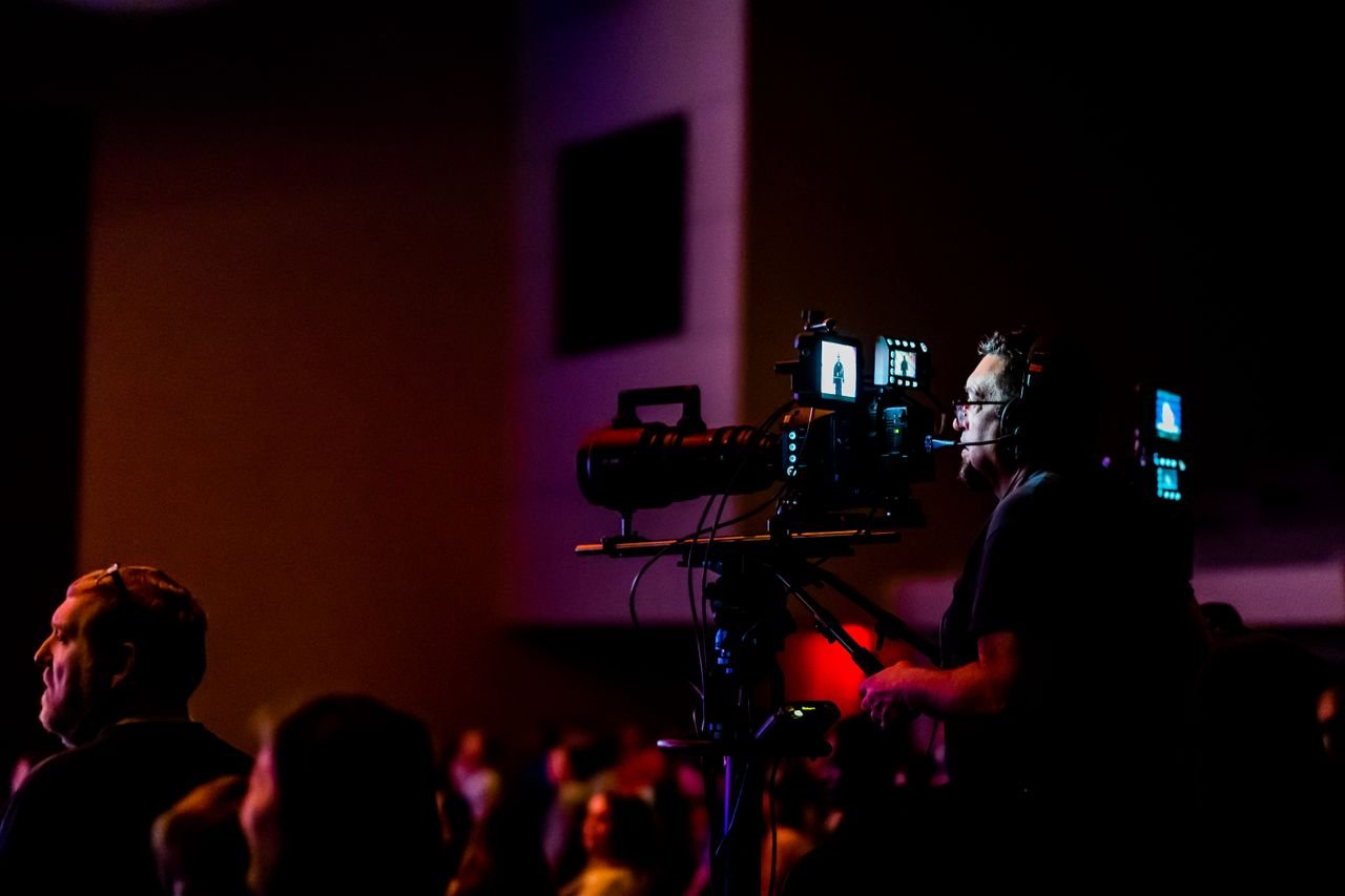 wedding-02 A videographer operates a camera during a live event, capturing the action professionally.
